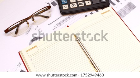 A notebook lies among the financial statements on the office desk.