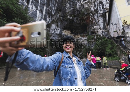 A woman taking a selfie with her smartphone and showing a peace sign with her fingers