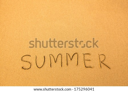 Summer, text written by hand in sand on a beach.