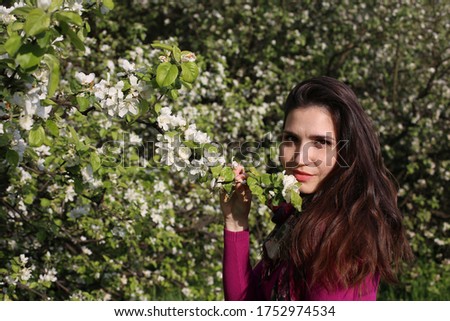 portrait of a beautiful woman with brown hair on a background of a blooming garden