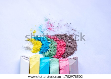 Colored powder and crayons, blue purple yellow isolated on white background