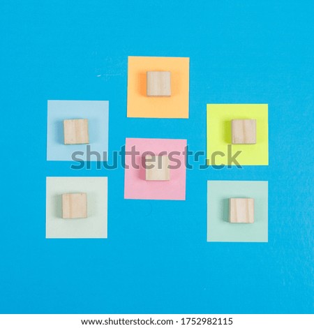 Notes idea concept with colorful sticky notes, wooden cubes on cyan blue background flat lay. horizontal image