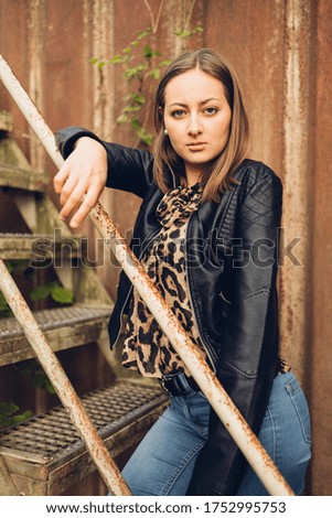 Young woman in leather jacket and jeans posing in a lost place