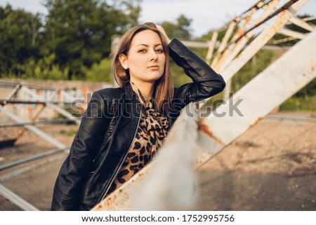 Young woman in leather jacket and jeans posing in a lost place