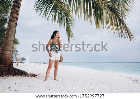 Asian woman talking on the phone at the beach