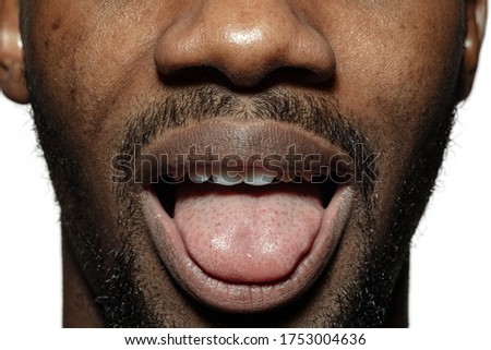 Gremacing. Close up of face of beautiful african-american young man, focus on mouth. Human emotions, facial expression, cosmetology, body and skin care concept. Fun, stick out the tongue.