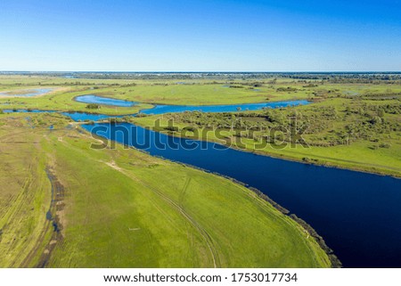 Scenic aerial view of a river and green fields in a countryside