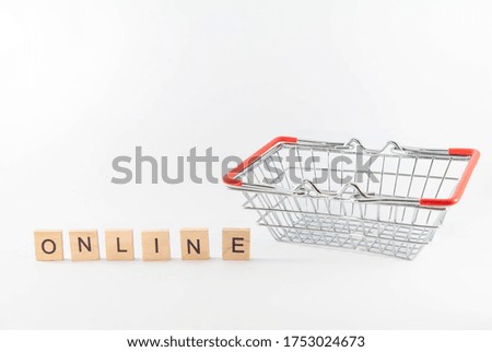 Online shopping. Shopping basket with wooden blocks "ONLINE" on white background. Concept of online shopping during coronavirus pandemic crisis. Selective focus with copy space.