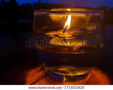 Candle light on dinner table - small beautiful candle light on a glass of water in the evening