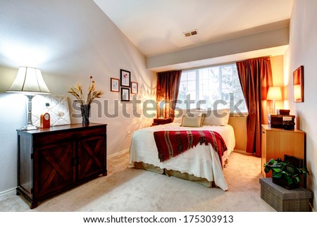 Cozy bedroom with high vaulted ceiling furnished with antique cabinet and queen size bed