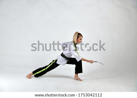 beautiful girl a fighter in a black and white kimono does exercises with fighting sickles