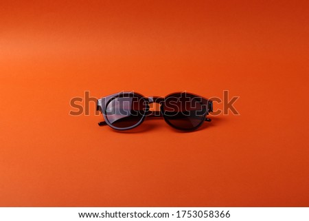 female or male classy and elegant sunglasses on the colorful bright orange background as the mean of sunprotection or fashion accessories. 