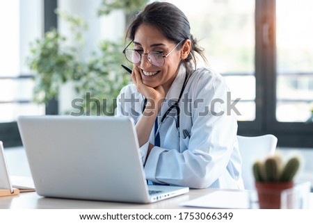 Shot of smiling female doctor working with her laptop in the consultation. Royalty-Free Stock Photo #1753066349