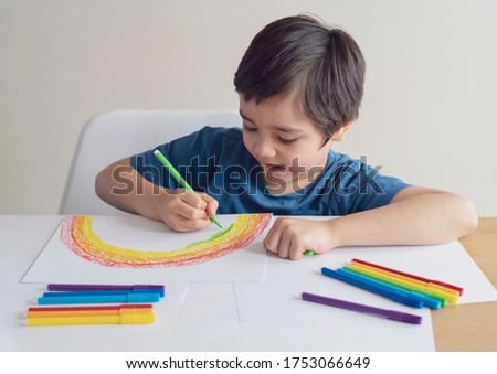 Kid using colour pen painting rainbow on paper,Child using digital tablet searching information on internet about rainbow color, Home schooling Social media campaign for coronavirus prevention concept