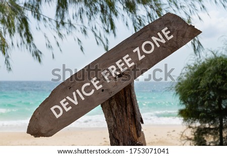 Old wooden sign with text device free zone on tropical beach. Rest from social media gadget and internet
