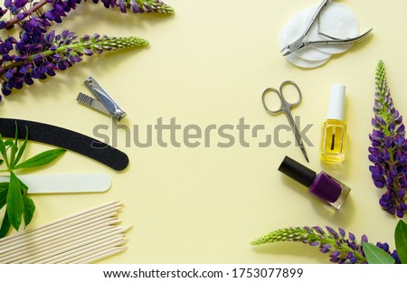 Manicure and pedicure items with lupin flowers on a light yellow background. Space for text