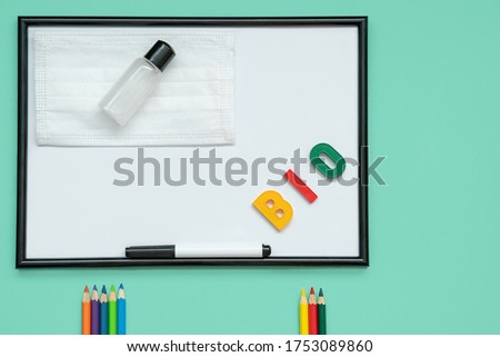 Back to school in a new reality, a medical mask, a sanitizer, stationery: pencils, letters. flat lay on the topic back to school
