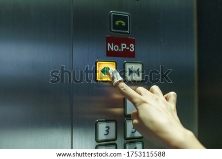 Woman wearing rubber for finger pressing a button of elevator button inside the building. void direct contact during the outbreak of Covid-19.
