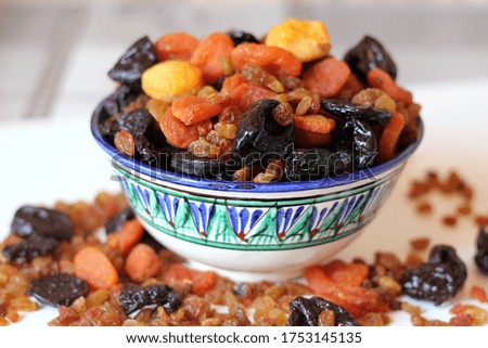 Dried fruits in a plate with oriental ornament. Oriental sweets on the table in a bowl.