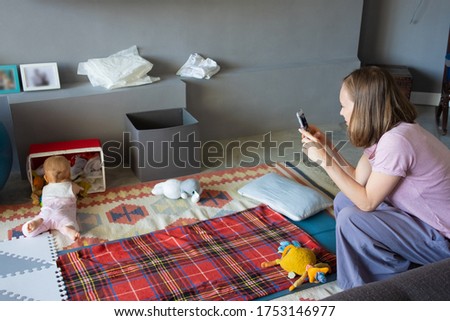 Mother taking photo or video of curious baby daughter at home. Baby checking box with stuff. Childhood or child care at home concept