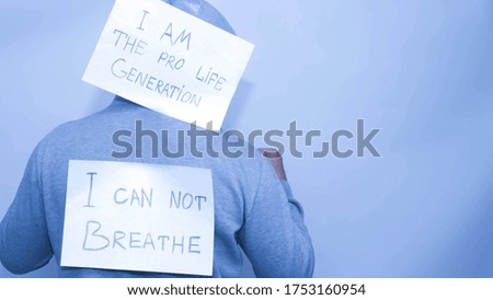 A man protests, the slogan I can’t breathe,on a white background,a man with posters on his back,i vote pro life