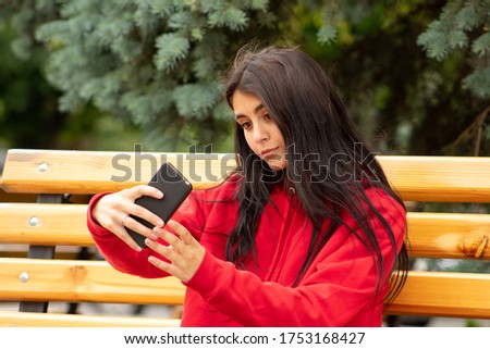 Young brown woman with her dark hair posing for a selfie on her smartphone