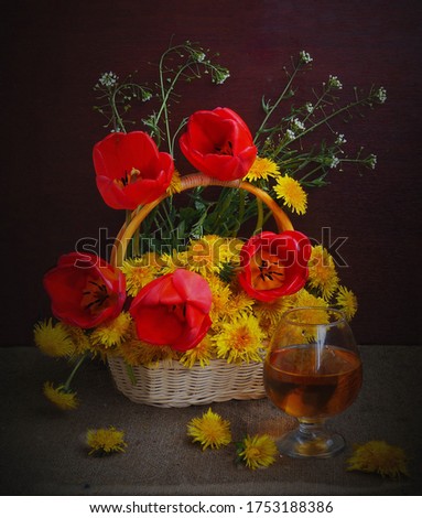 The picture was taken in the spring of the year 2020.The picture shows a bouquet in a basket with red tulips and yellow dandelions.