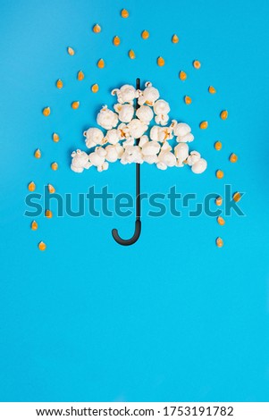 Umbrella and poruing rain drops made out of popcorn on a blue background