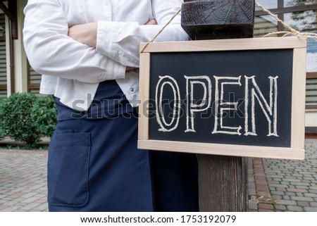 Woman's hands holds dashboard with text open. Worker shows advertising opening of the cafe or restaurant.