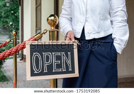 Woman's hands holds dashboard with text open. Worker shows advertising opening of the cafe or restaurant.