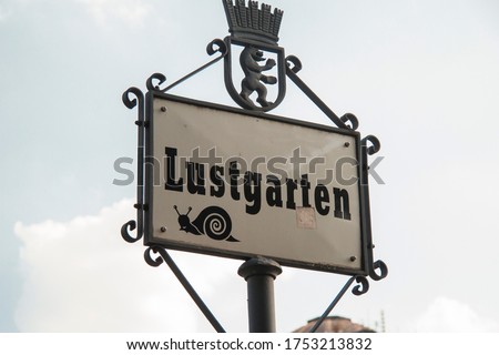 close-up detail Iron sign of Lustgarten (garden of pleasure) with the Berlin bear on top and the drawing of a snail on the poster itself on a cloudy day from Berlin Germany