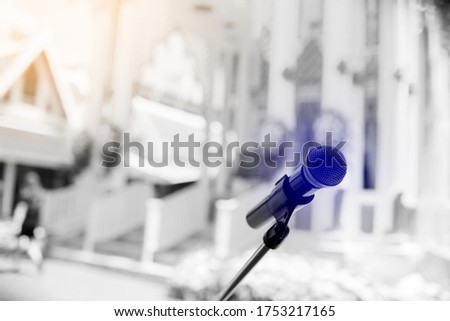 Black and white image. Microphone with blurry outdoor location for Buddhist activities. The concept of speaker.