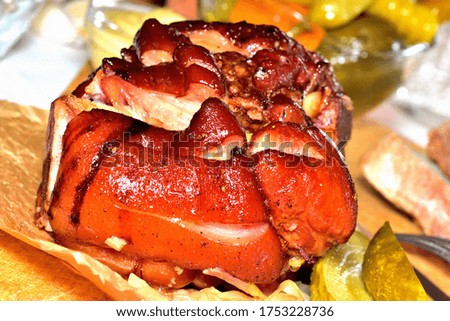 Close-up of roasted smoked pork knuckle on onion with garlic, honey, pickles, mustard and spices