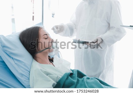 Infected patient woman with breathing respiratory equipment lying in bed,  doctor wearing protective clothing take care of the sick at disease treatment room quarantine at hospital
