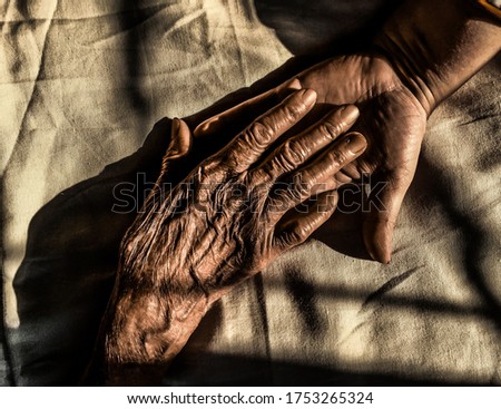 Young daughter holding old mothers hand