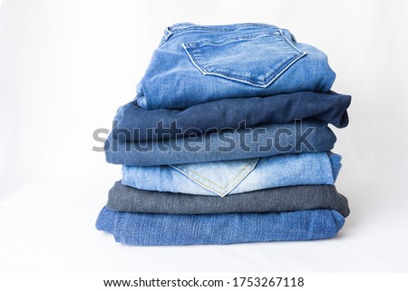 A orderly stack of variety blue jeans on the white background.  Studio shot.