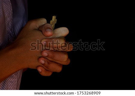 Human hand holding the cross black background
