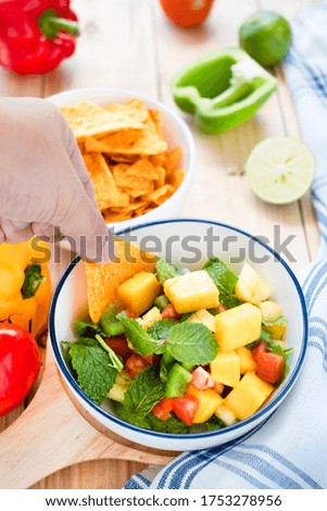 Mexican mango salsa salad with taco & fruits on wooden table background. Fresh Mango salsa salad is a healthy Mexican cuisine. Eating traditional Mexican mango salsa salad with taco is healthy.   