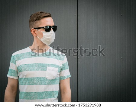 A man wearing a medical protective mask. looking to the left.On a Gray background. During the coronavirus pandemic
