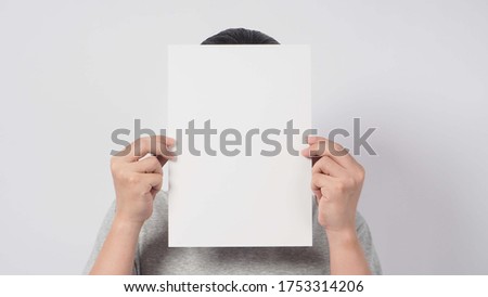 Male's hands is holding the A4 paper and wear gray t shirt on white background.