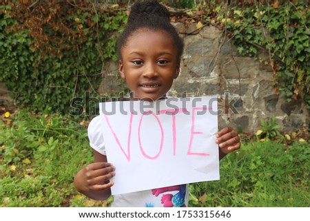 Kid holding white sign with word vote outside