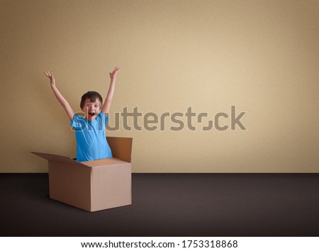 The boy jumps out of a cardboard box. The concept of thinking outside the box.