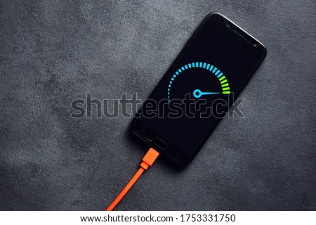 Smartphone connected to a usb charging cable and fast charging on black background. Phone fast and quick speed charge.  Royalty-Free Stock Photo #1753331750