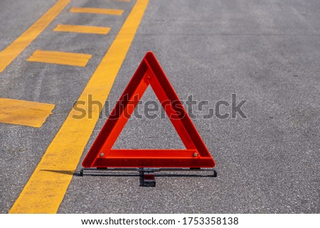 Emergency red warning triangle on the road sign with yellow traffic line