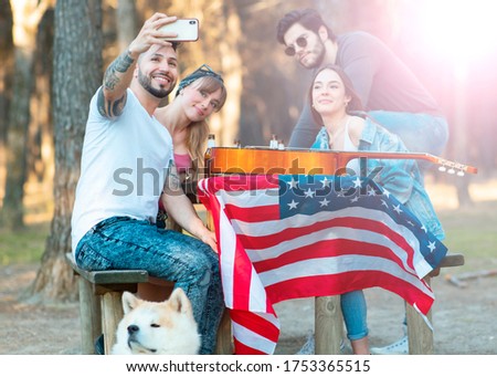 Happy friends having fun outdoors, picnic, young people cheering mobile doing seflie on summer evening weekend - Friendship
