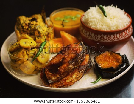 Bengali Platter, It comprises of Steamed Rice,Egg Plant Fry,Fish Fry,Raw Bananas Fry,Pointed Gourd Curry, Lentils and Mangoes. It is served traditionally in Bengali Homes. Royalty-Free Stock Photo #1753366481