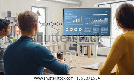 Team of Analytics, Economists, Young Businesspeople Hold Meeting Presentation use Shows Digital Interactive Whiteboard with Growth Analysis, Charts, Statistics and Data. People Work in Creative Office
