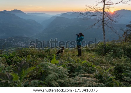 Woman with a camera shooting the landscape at sunrise from a lookout