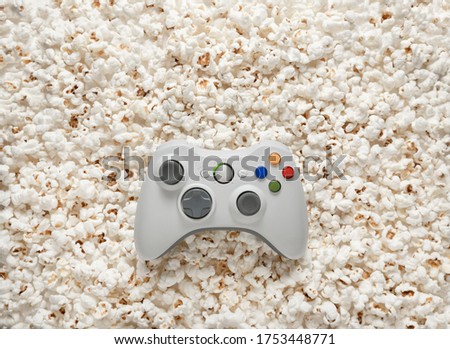 White gamepad on popcorn background. Game poster or postcard concept. Rest for the game and popcorn.