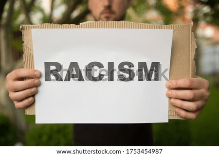 Young man holding racism cardboard in hands
